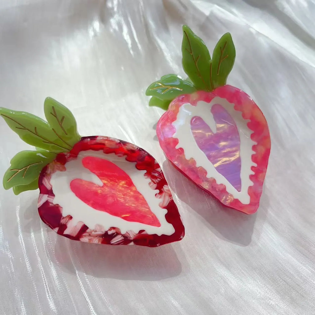 Red and pink strawberry decorative hairpin barrette clip on white background.