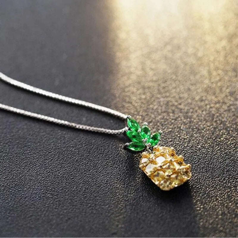 Women's silver tone necklace with a geometric pineapple and diamond motif pendant on a chain.