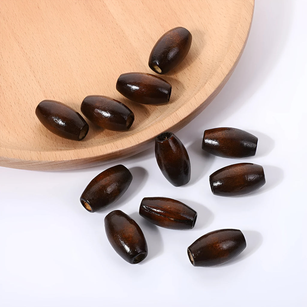 Dark coffee coloured oval wooden bead with an M-shaped raised design on a white background.