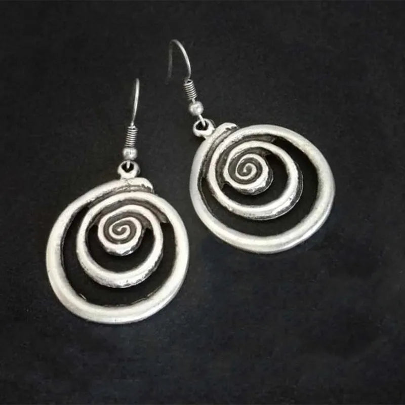 Silver geometric spiral earrings with a distressed texture on a white background.