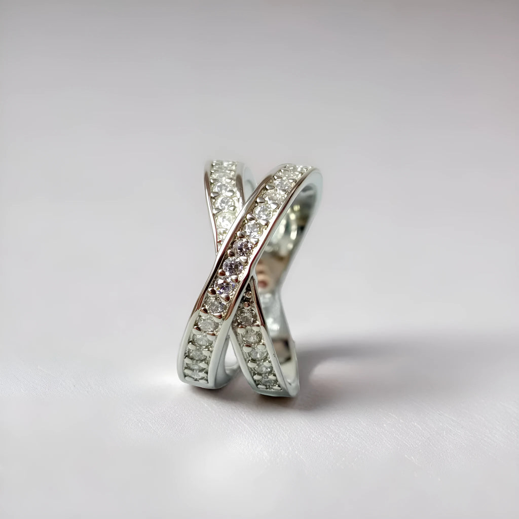 A silver or rose gold electroplated metal cross ring with micro-inlaid zircon stones, showing geometric and heart-shaped design.