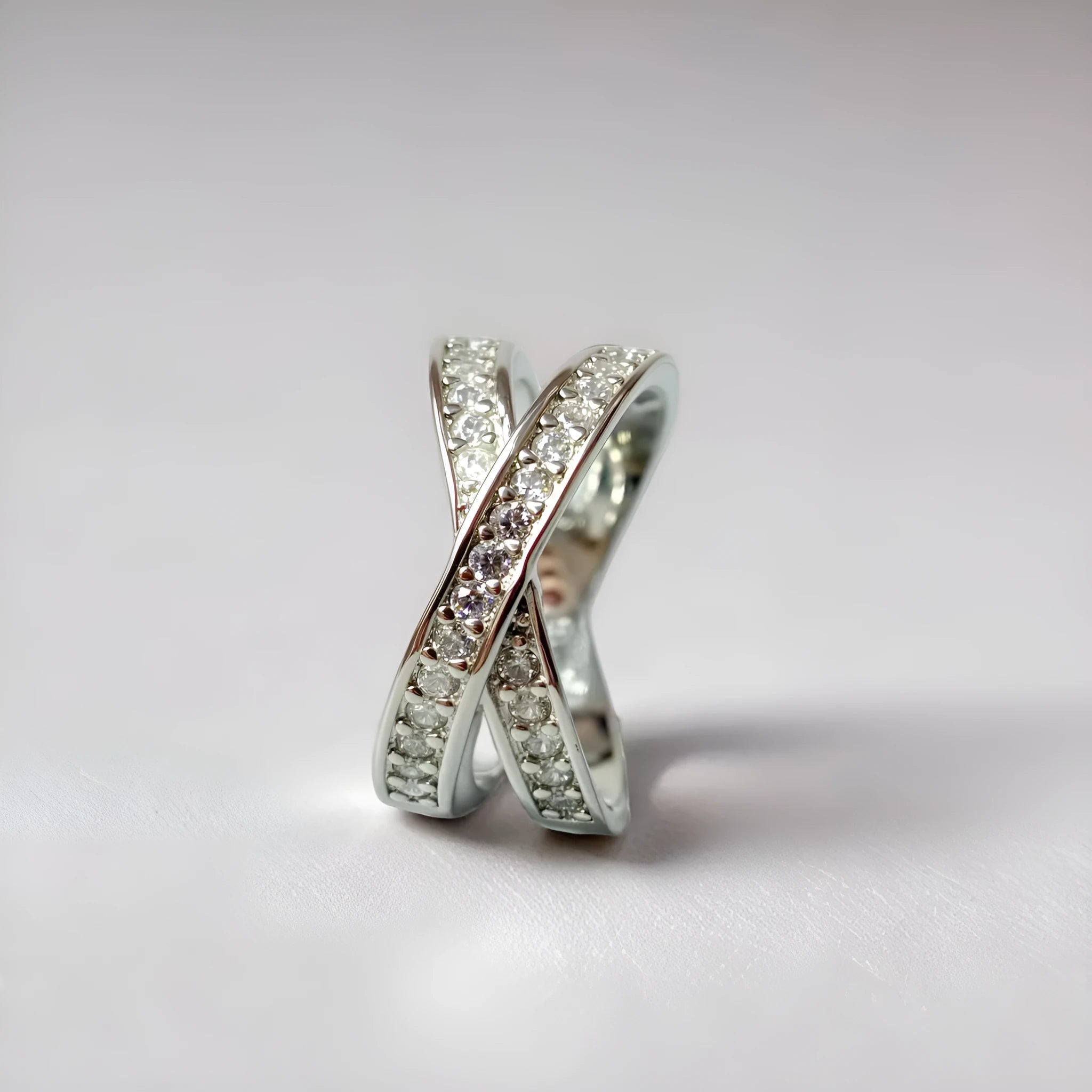 A silver unisex ring showing a cross design with micro-inlaid zircon stone details on a geometric band.