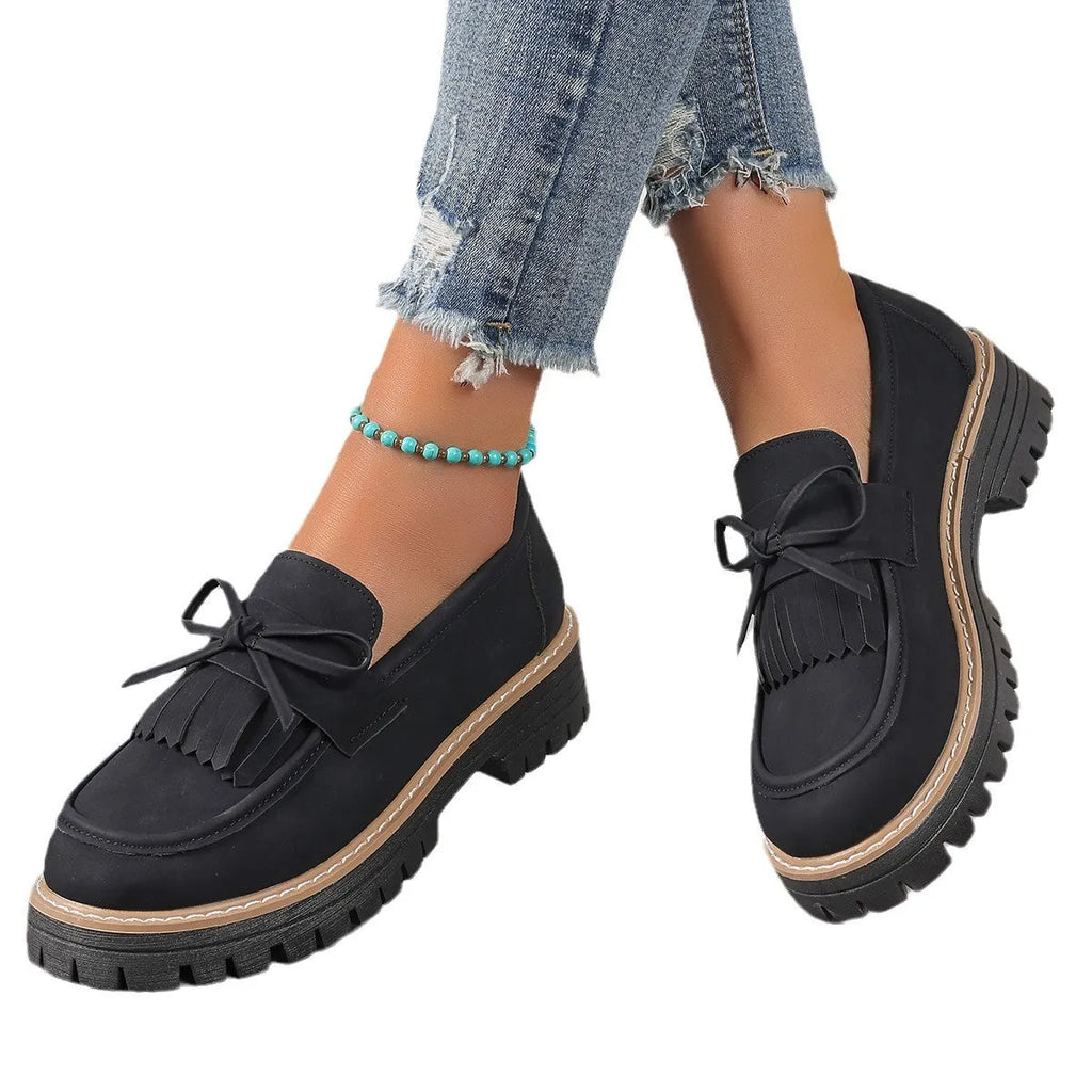 Black and brown plus size women's loafers with tassel detail, chunky heel, and round toe.