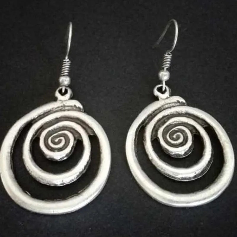 Silver geometric spiral earrings with a distressed texture on a white background.