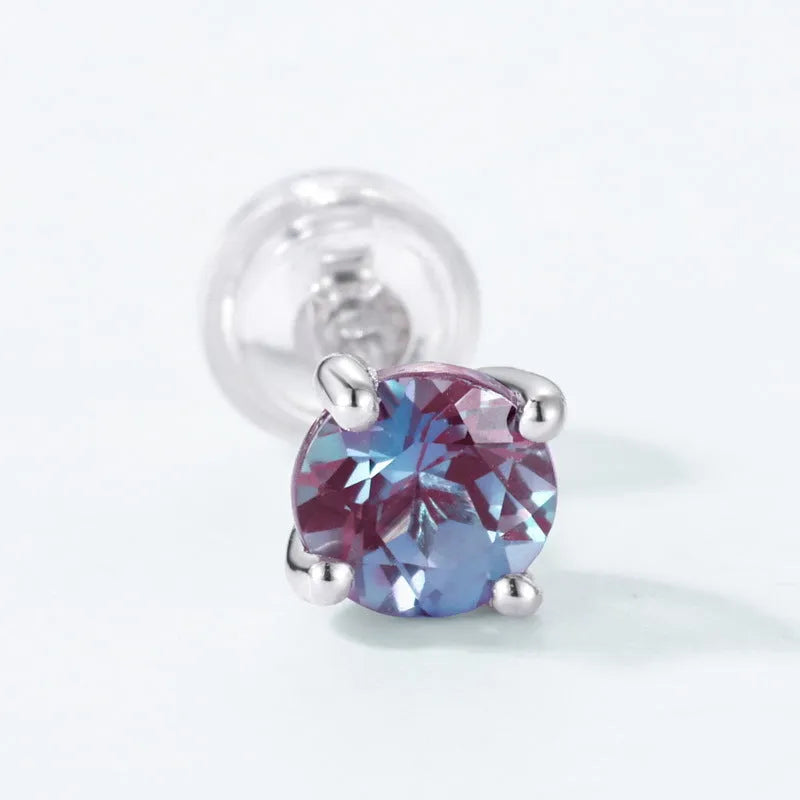 A pair of simple style silver ear studs with a round cultivated Alexandrite stone in a geometric setting.