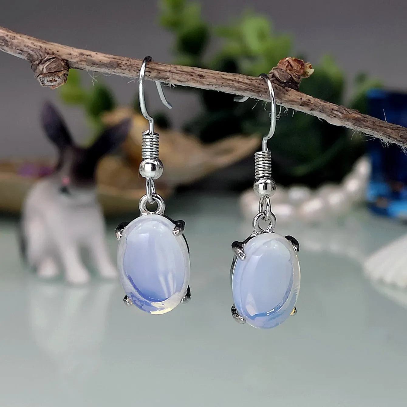 Moonlight white opal earrings with retro drop shape and cross charm detail