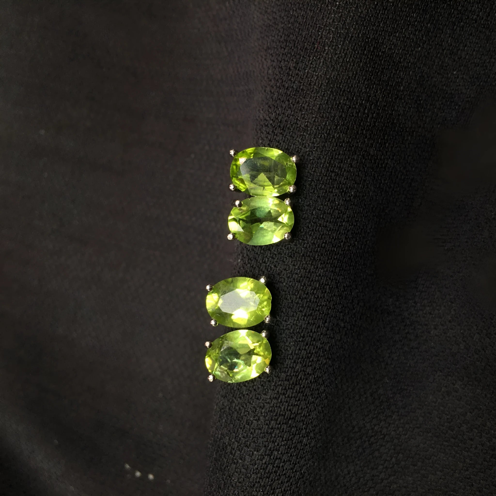 Close-up of natural grass green olivine stud earrings in S925 silver setting.