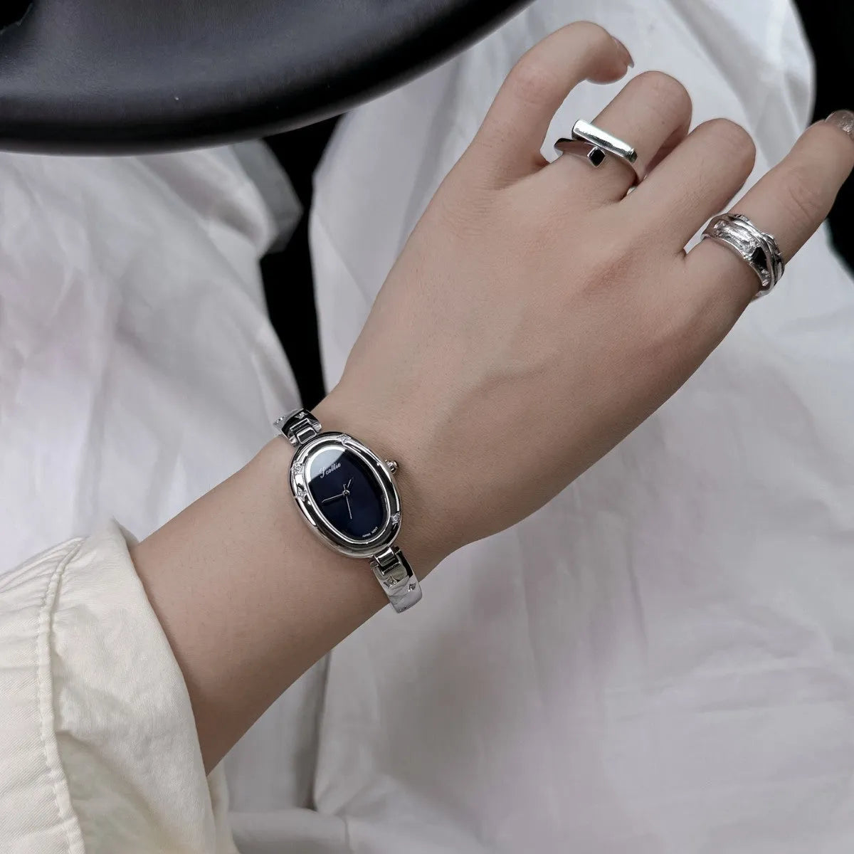 Oval disk bracelet watch with mineral glass mirror and rose gold clasp on a light background