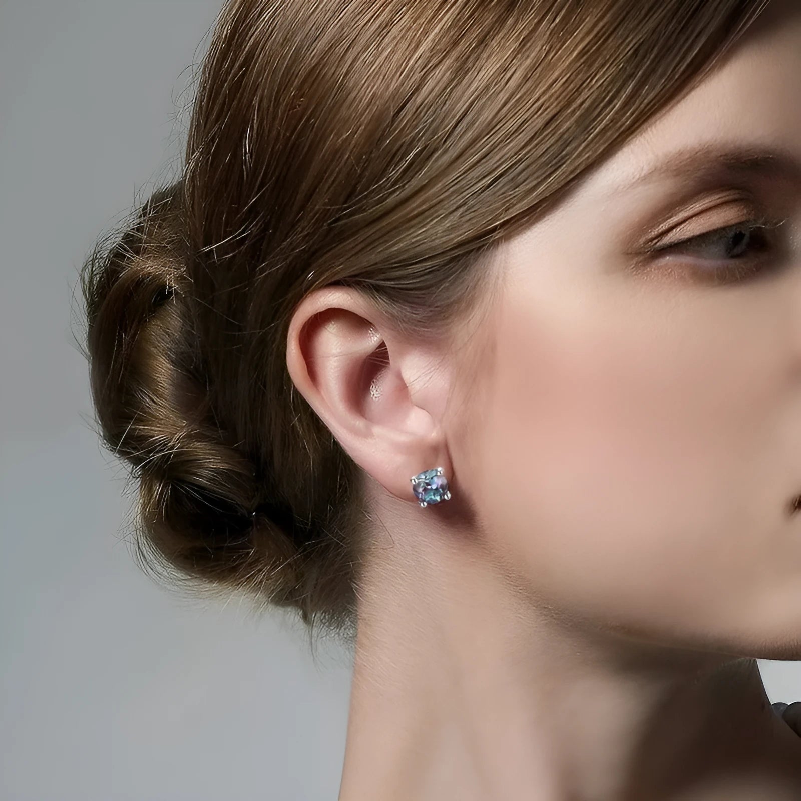 A pair of simple style silver ear studs with a round cultivated Alexandrite stone in a geometric setting.