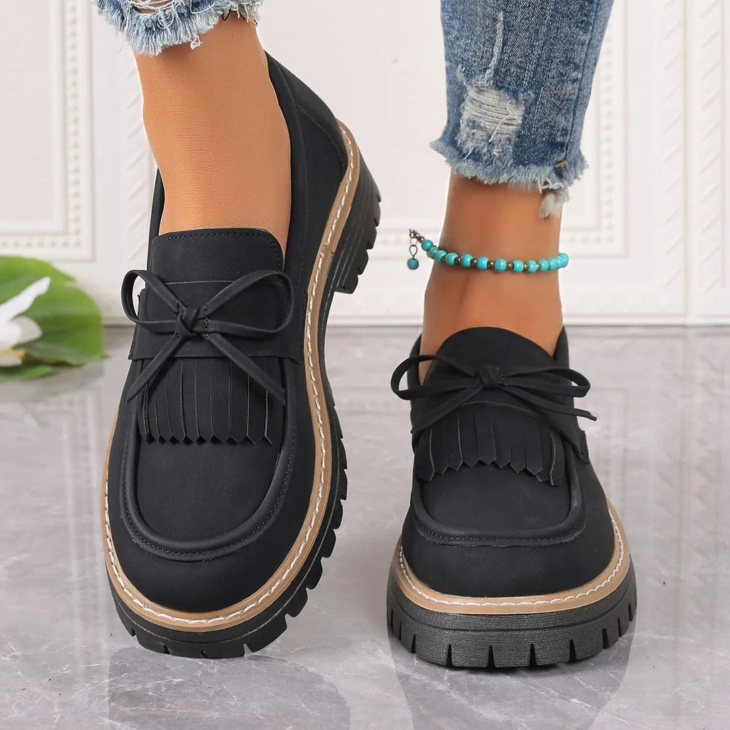 Black and brown plus size women's loafers with tassel detail, chunky heel, and round toe.