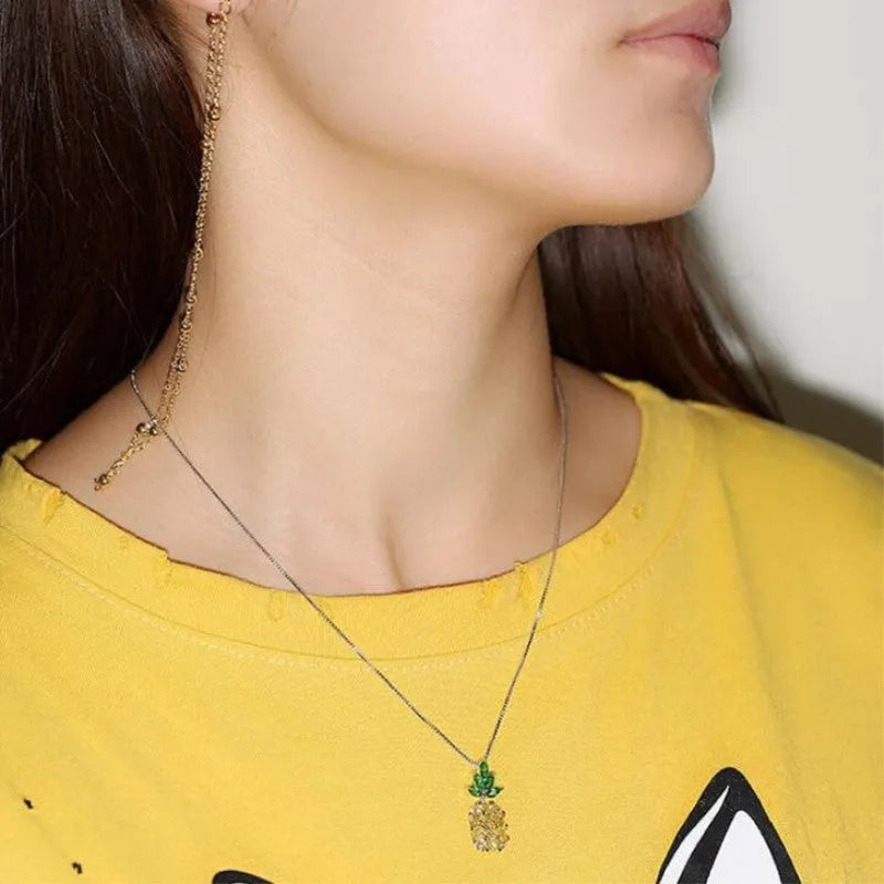 Women's silver tone necklace with a geometric pineapple and diamond motif pendant on a chain.
