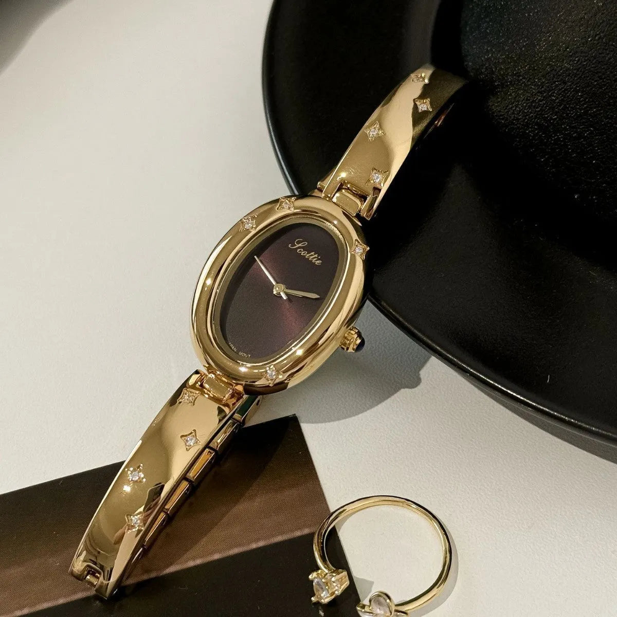 Oval disk bracelet watch with mineral glass mirror and rose gold clasp on a light background