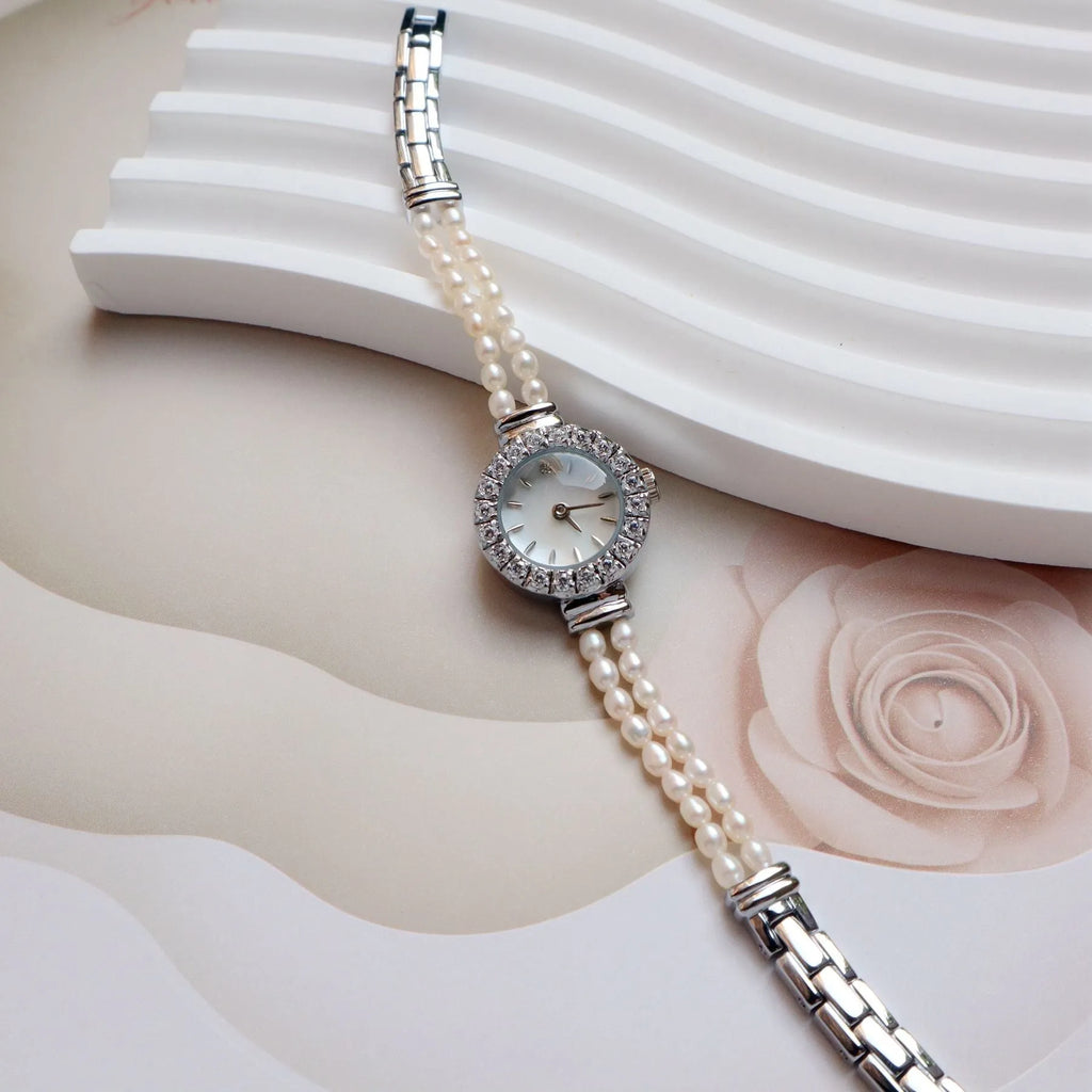 Women's light gold bracelet watch with natural freshwater pearls on a stainless steel strap, showing an 18mm round dial.