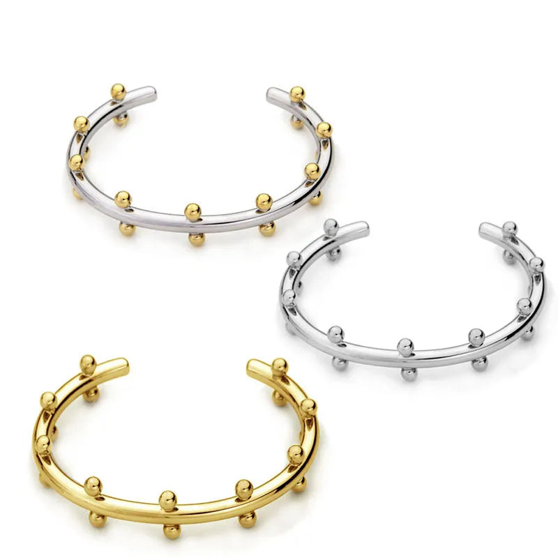 Stainless steel C-shaped bead with textured rivet detail and an alloy bracelet.