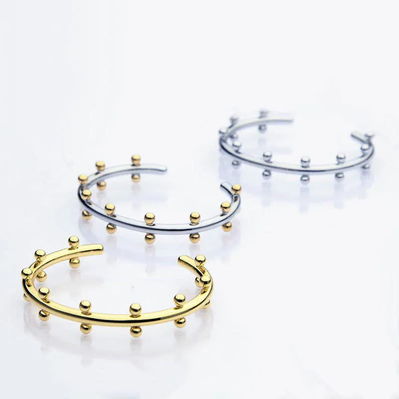 Stainless steel C-shaped bead with textured rivet detail and an alloy bracelet.
