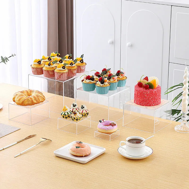 White acrylic six-piece cube dessert display stand arranged on a table with cupcakes.