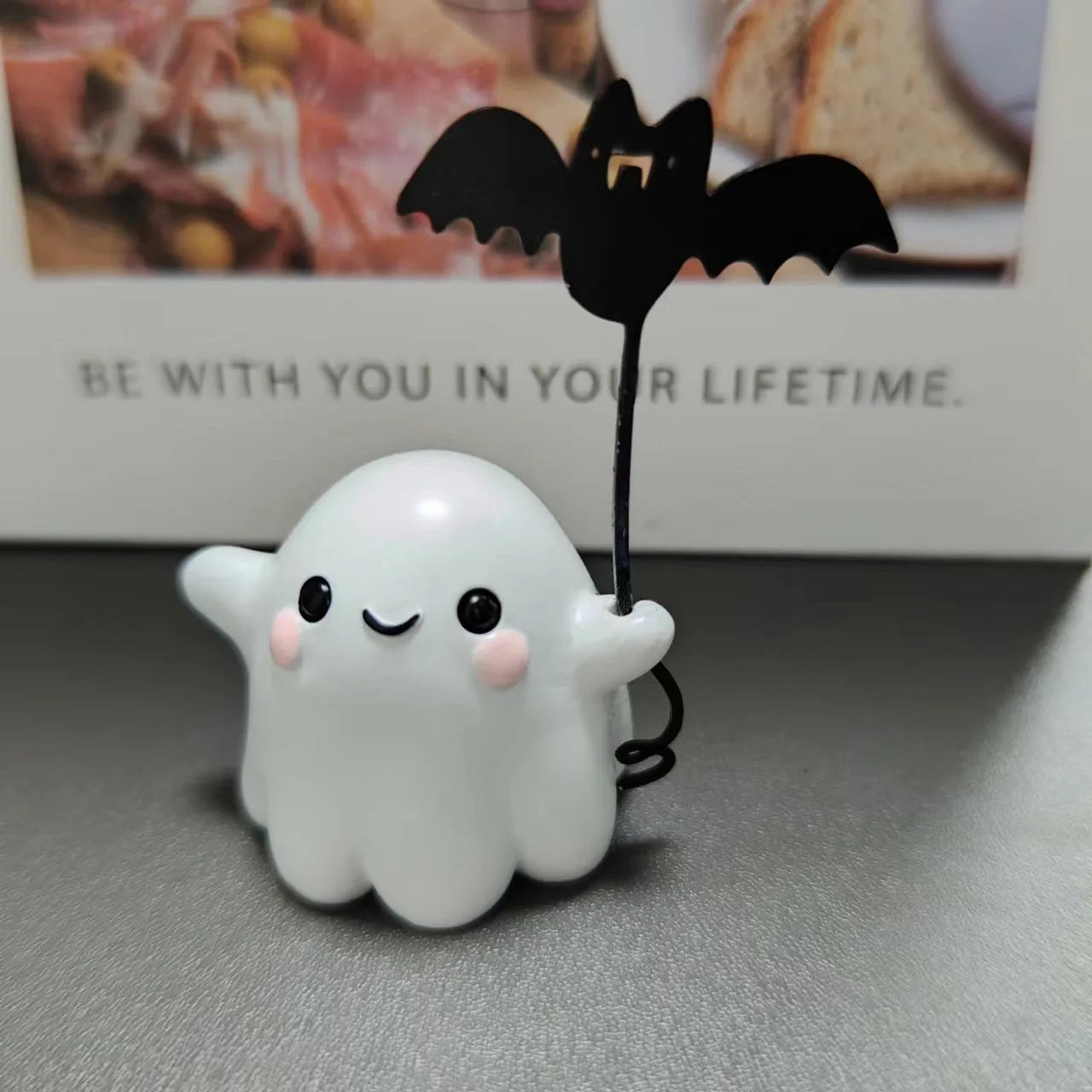 Miniature hand-painted resin statue of a cartoon ghost walking a bat, a Halloween ornament.