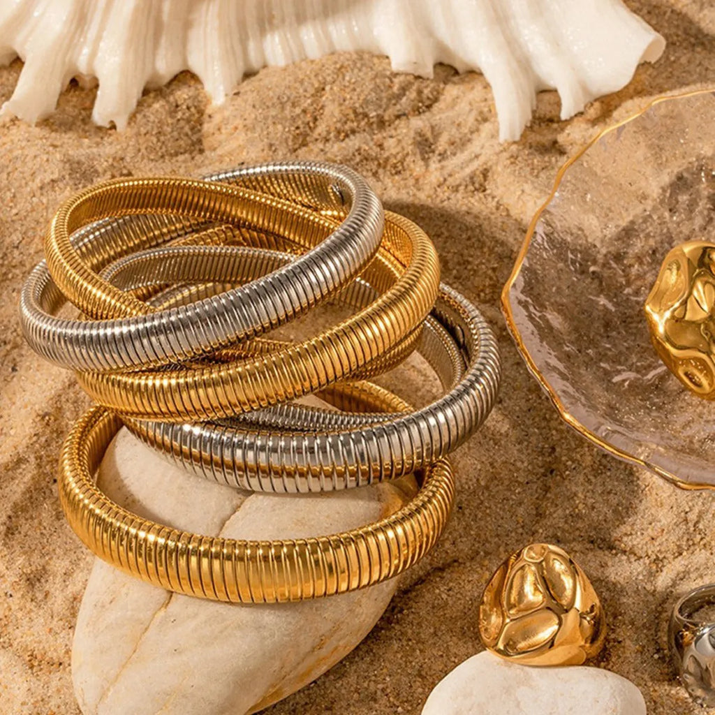 Gold elastic titanium steel bracelet with a wide vertical stripe ring pattern on a wrist.