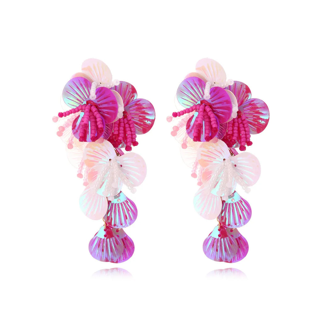 Colourful handmade bead and string flower earrings in exaggerated dopamine style on a purple background.