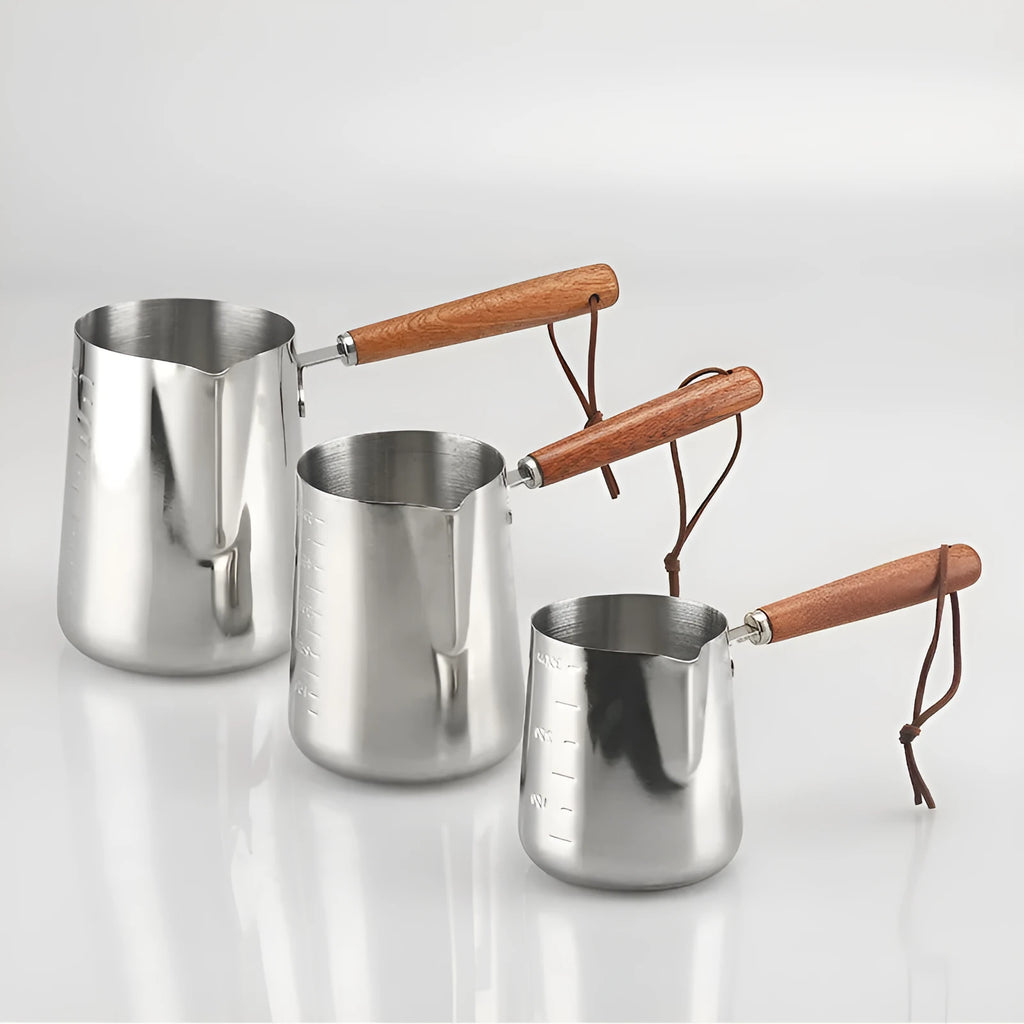 Stainless steel milk frothing cup with wooden handle showing interior measurement scale markings