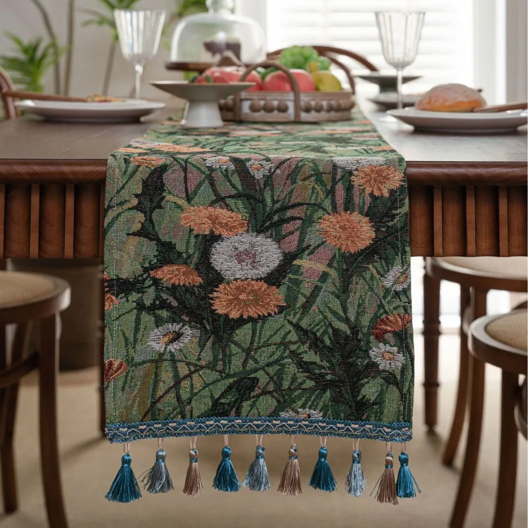 Long beige jacquard table runner with floral pattern and knotted tassels on a wooden dining table.