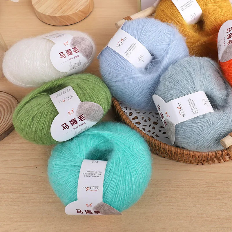Hand-woven DIY mohair scarf kit with wool ball, shown in a selection of colours including beige, pink, and blue.