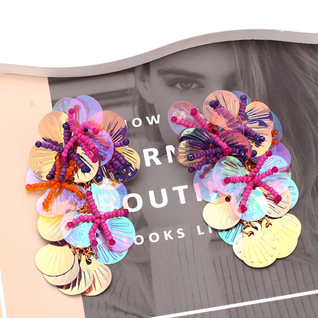 Colourful handmade bead and string flower earrings in exaggerated dopamine style on a purple background.