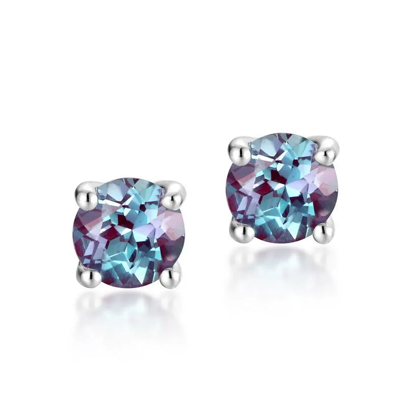 A pair of simple style silver ear studs with a round cultivated Alexandrite stone in a geometric setting.