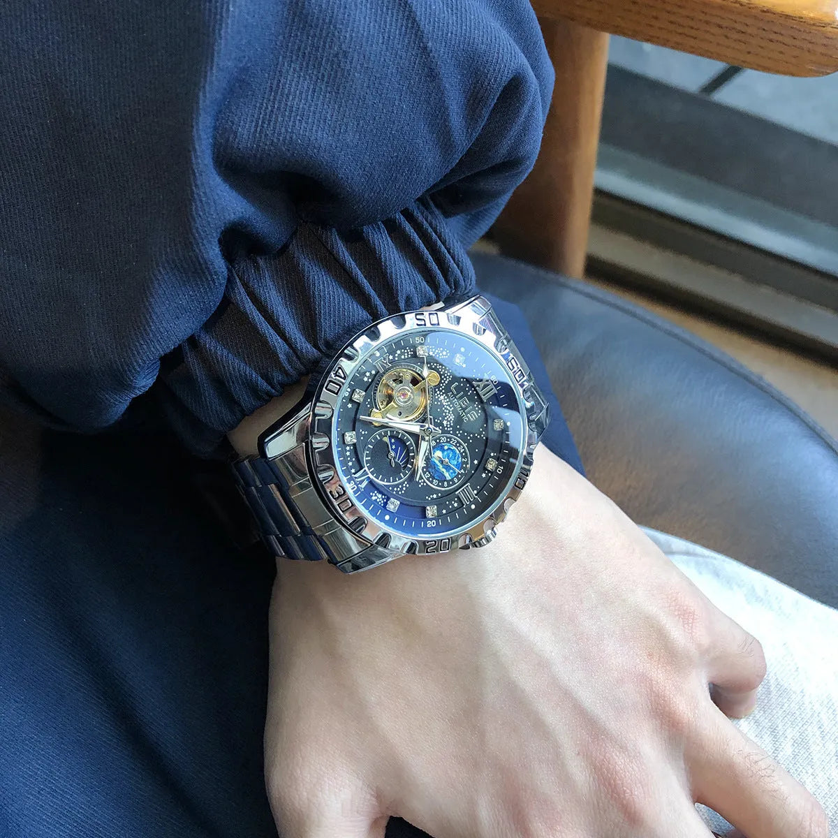 Men's silver case automatic watch with starry black luminous dial and brown leather strap.