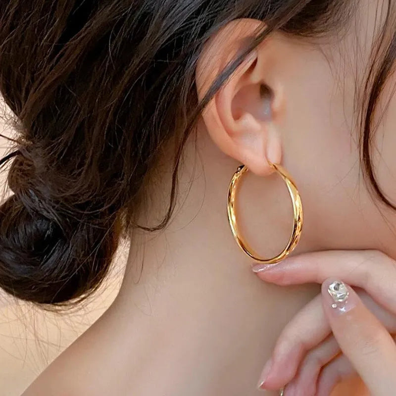A pair of gold metal circle hoop earrings with a 40mm diameter on a plain background.