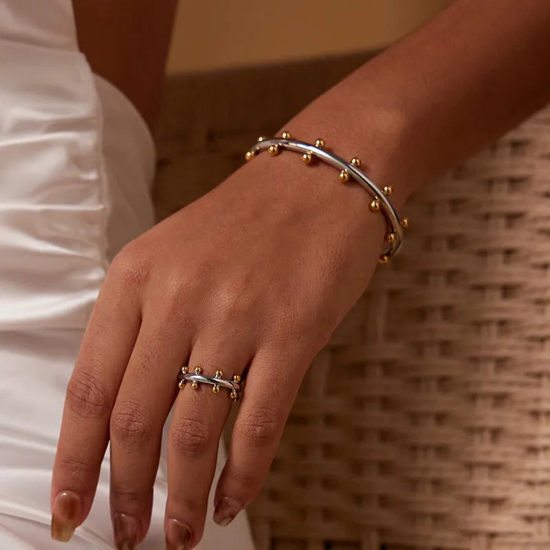Stainless steel C-shaped bead with textured rivet detail and an alloy bracelet.