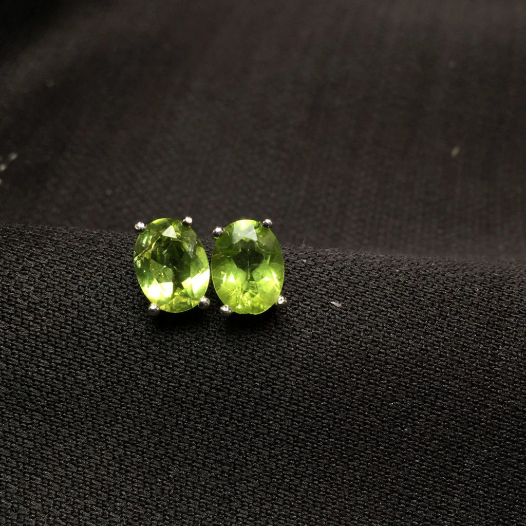 Close-up of natural grass green olivine stud earrings in S925 silver setting.