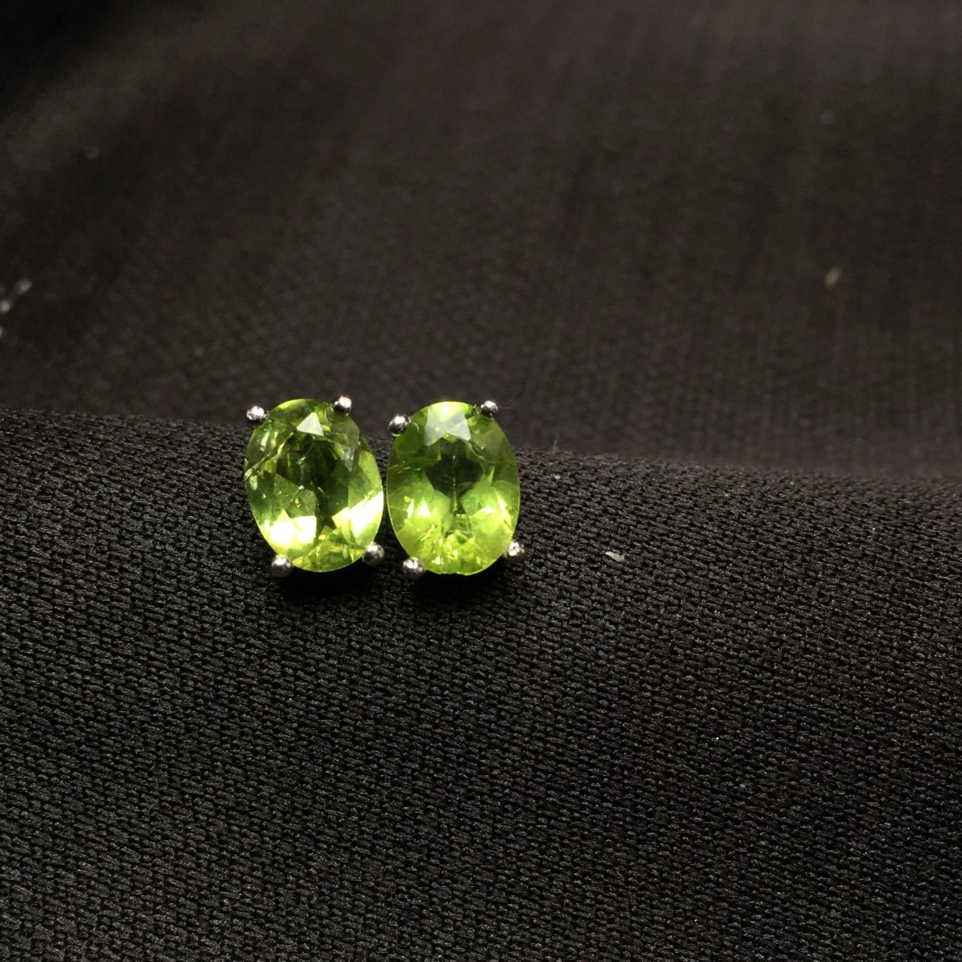 Close-up of natural grass green olivine stud earrings in S925 silver setting.