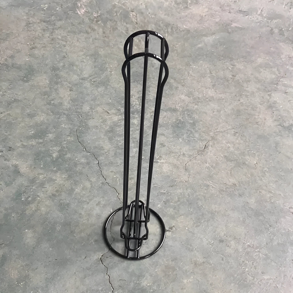 Black wrought iron coffee capsule storage rack holding pods on shelves.