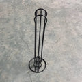 Black wrought iron coffee capsule storage rack holding pods on shelves.