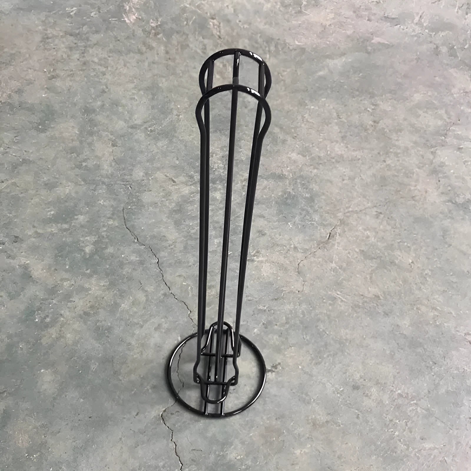 Black wrought iron coffee capsule storage rack holding pods on shelves.