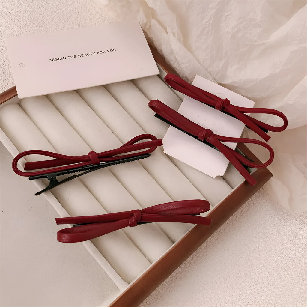 Wine red leather bow hair barrette with a metal clip on a white background