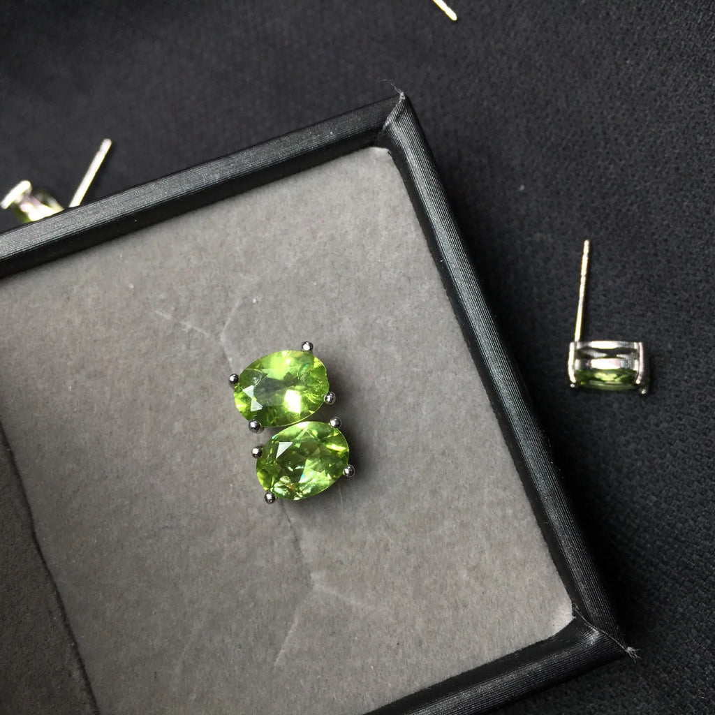 Close-up of natural grass green olivine stud earrings in S925 silver setting.