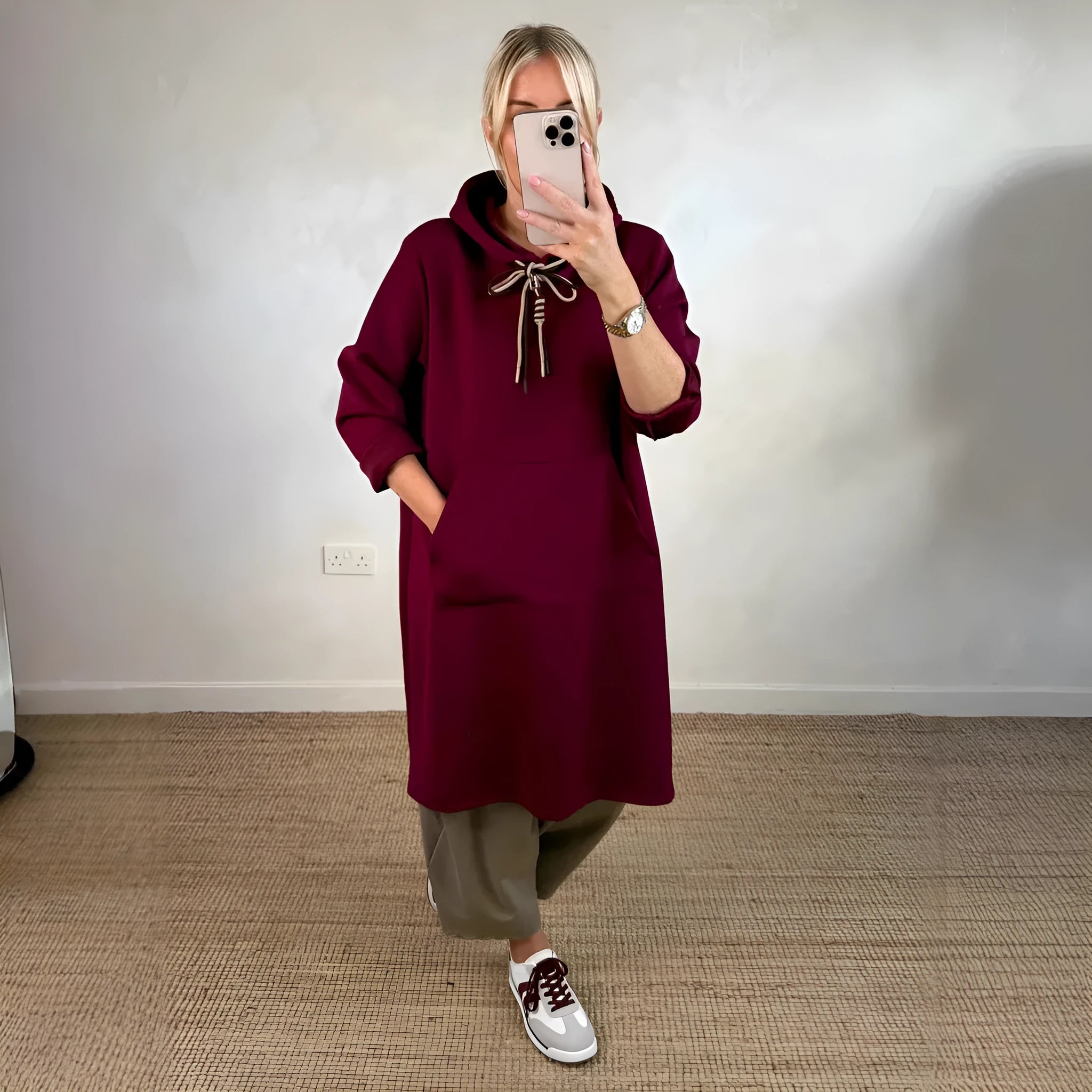 Woman wearing loose oversized knit hooded maxi dress in solid colour with front pockets, pullover style, black colour option