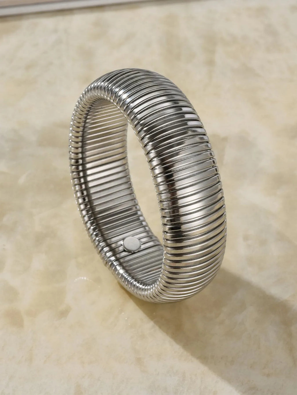 Gold elastic titanium steel bracelet with a wide vertical stripe ring pattern on a wrist.