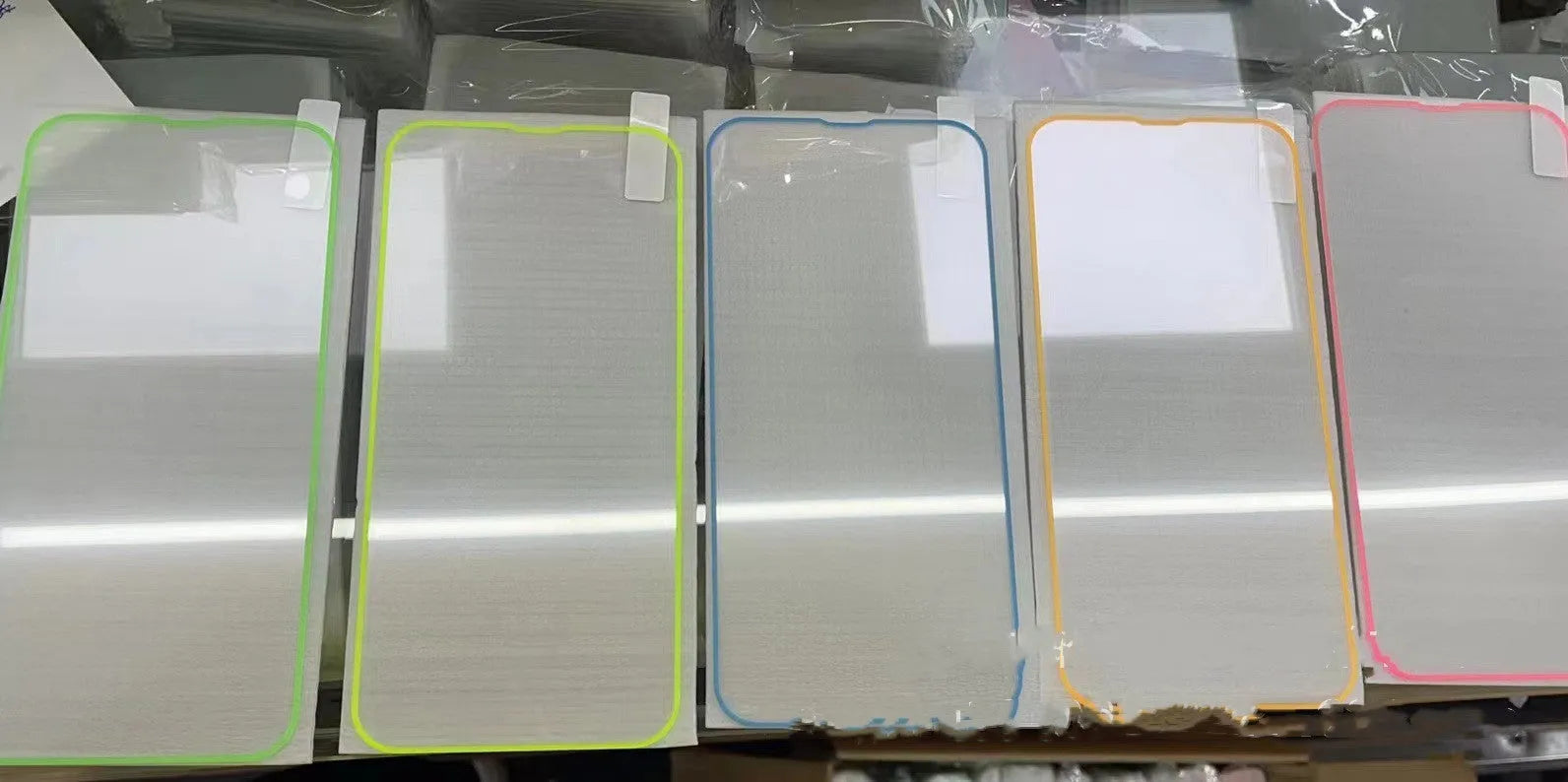 Fluorescent pink luminous tempered glass screen protector applied on an iPhone 13, glowing softly in a dark setting.