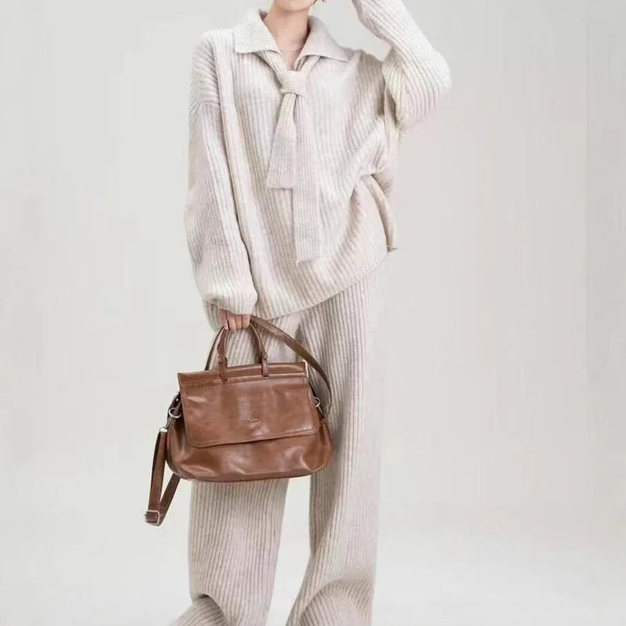 Beige women's knitted acrylic sweater and trouser two-piece set laid flat.