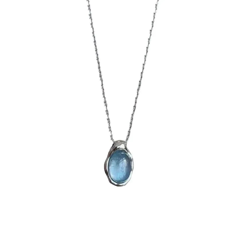 Close-up of a navy blue geometric water drop pendant on an adjustable silver-tone cross chain necklace.