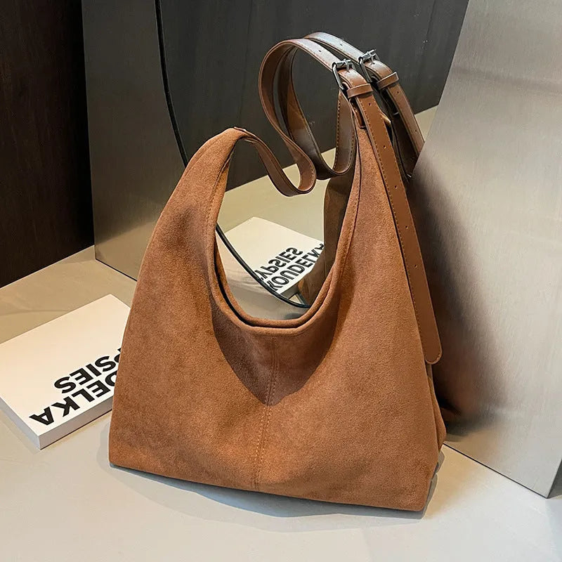 Women's suede bucket bag in black with stitching detail, single shoulder strap, and outer sandwich pocket