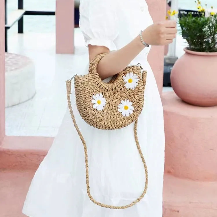Women's light brown straw-weaved crossbody bag with daisy decoration showing woven texture