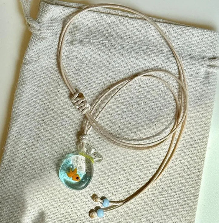 Women's coloured glaze pendant necklace on a braided cotton and linen clavicle chain, showing artisan finish.