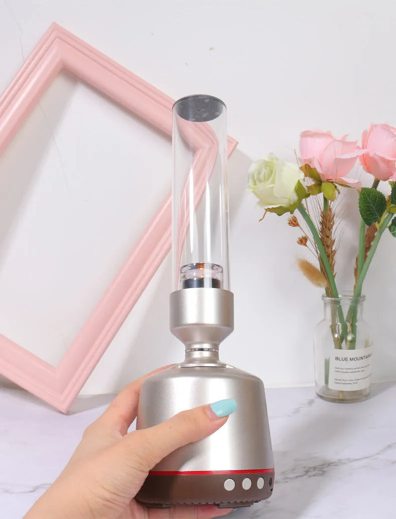 White silver cylindrical Bluetooth speaker with candlelight glow, showing push buttons, dimensions 90mm by 277mm.