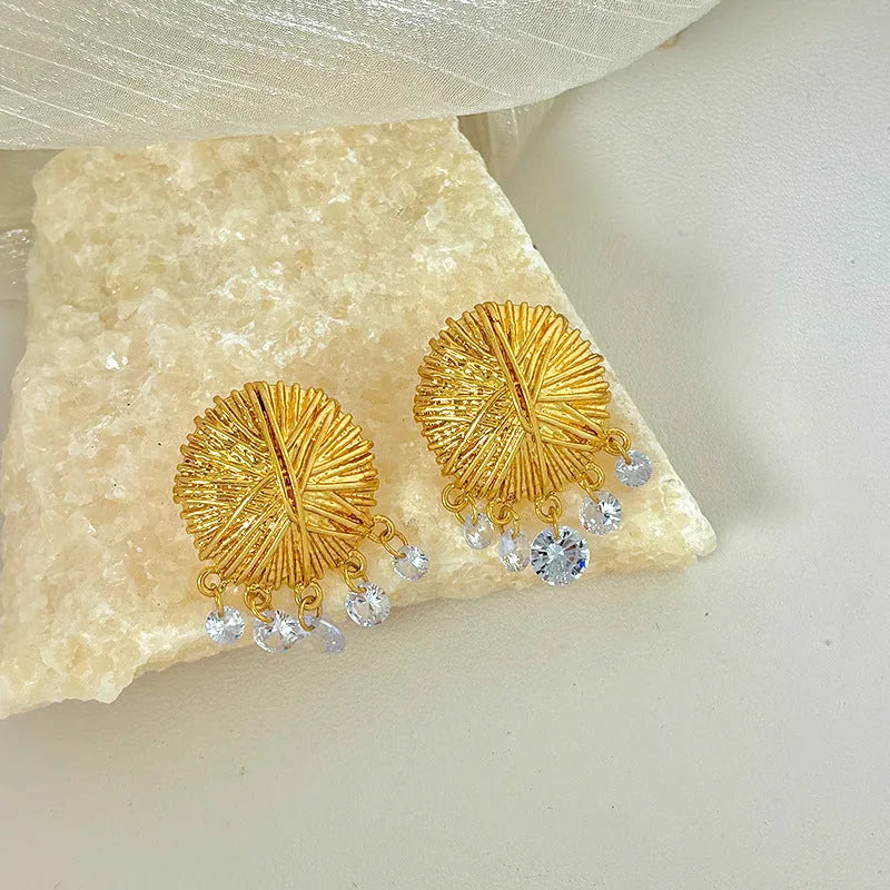 A pair of circular gold geometric hoop earrings on a plain background