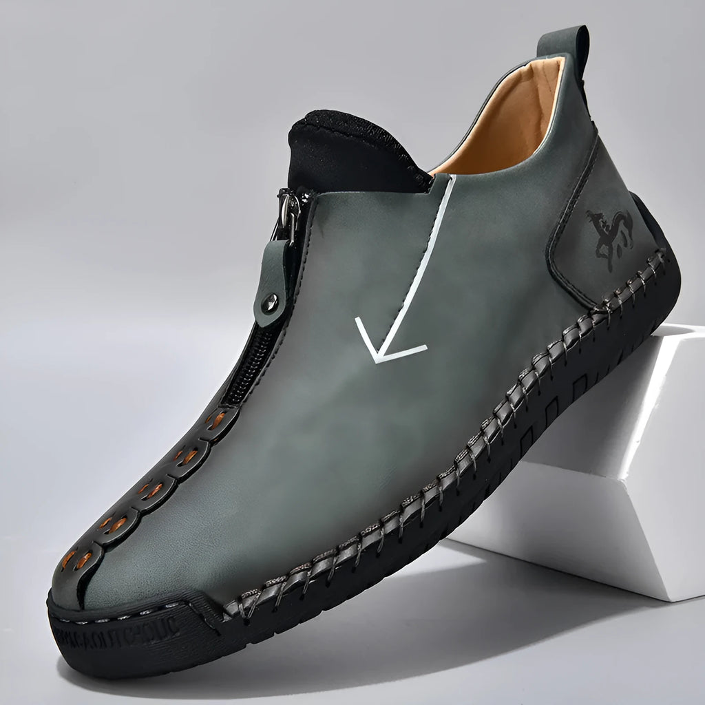 Men's black leather ankle boots with a front zipper and hand-stitched rubber sole.