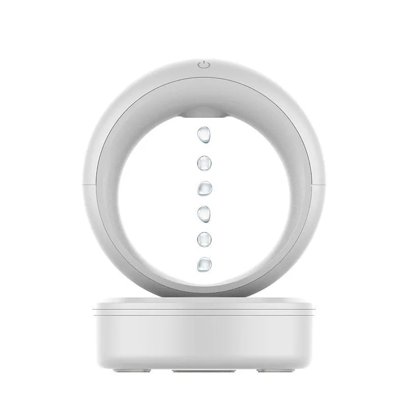 White round anti-gravity humidifier showing optical illusion of levitating water droplets on a desk.